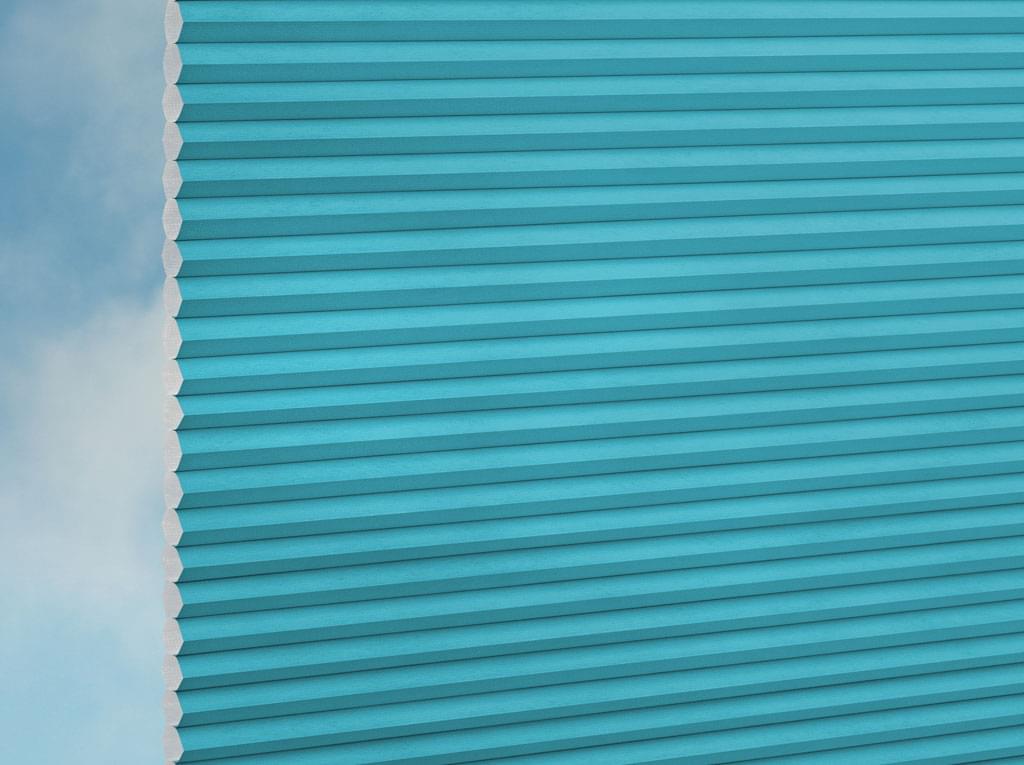 Nahaufnahme der DUETTE® Fixé Unix (1.7646) Türkis-Jalousien von Duetteshop mit türkisfarbenem Wabenmuster vor einem sanften hellblauen Hintergrund, der die detaillierte Textur und Struktur hervorhebt.